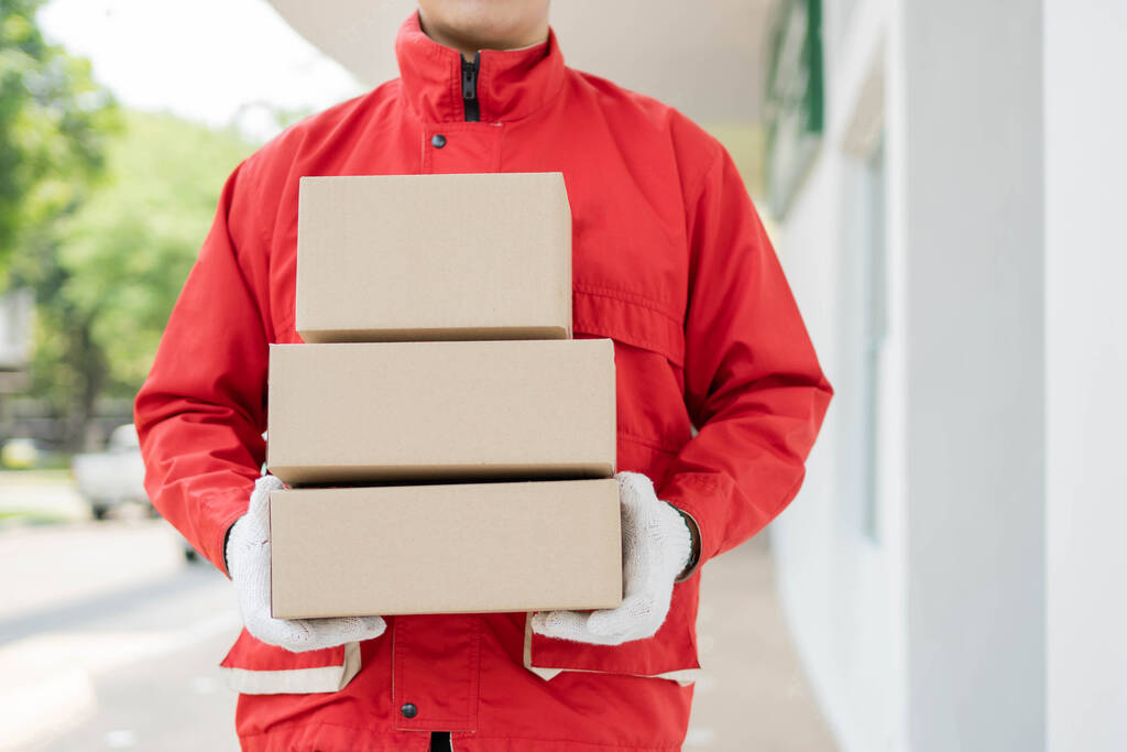 parcel delivery concept the mailman standing, holding three boxe